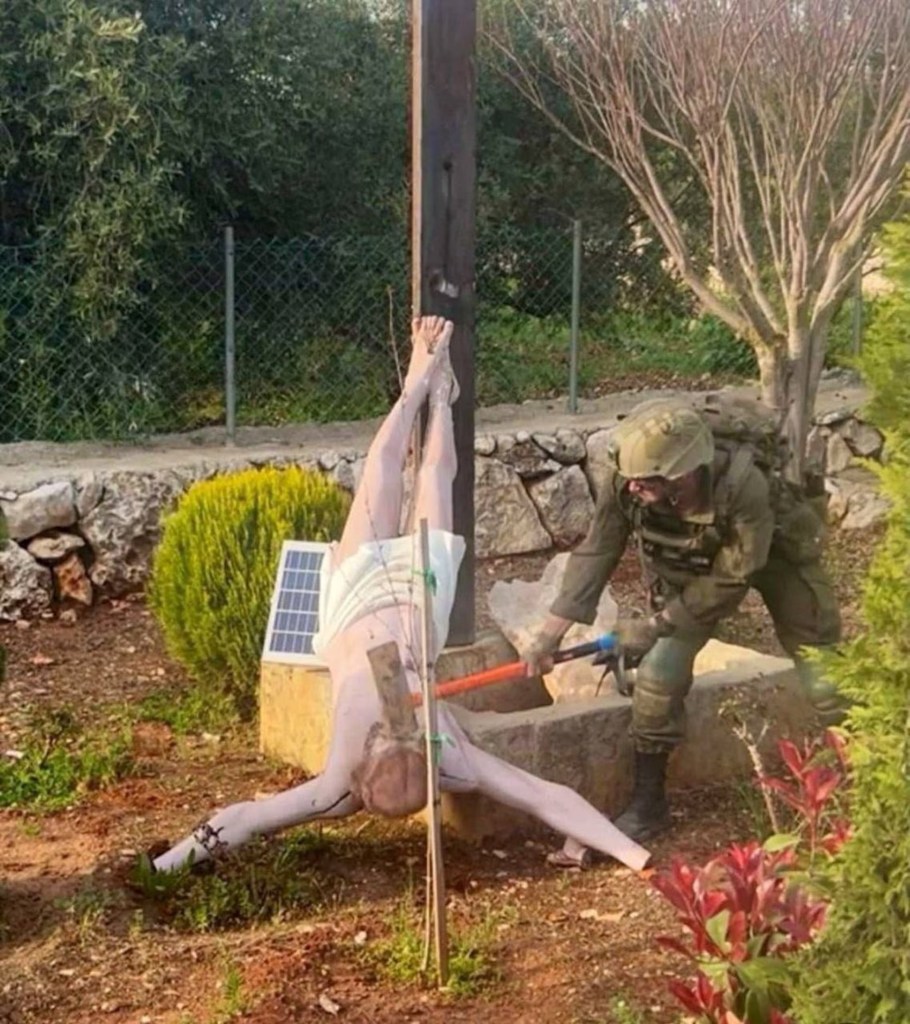 An Israeli soldier damages the head of a statue of Jesus, in Debel, Lebanon.